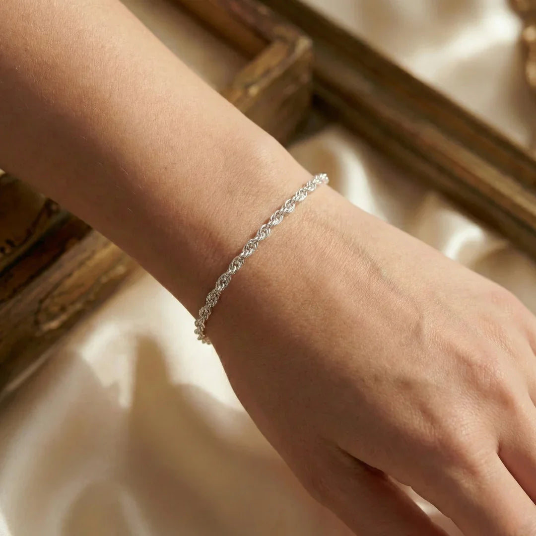 Pulseira de prata 925 com elo torcido no pulso feminino, joia delicada e elegante.